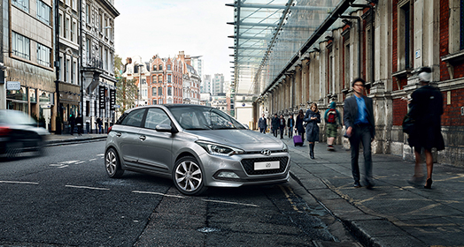 Side-front view of dark gray i20 parked next to pedestrian road